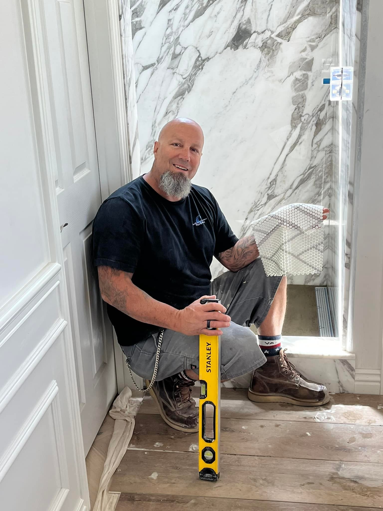 Eric, owner of Cutting Edge Tile & Stone, setting tile on a job site
